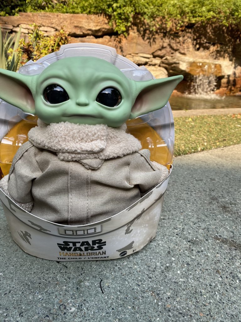 Baby Yoda in front of a body of water.